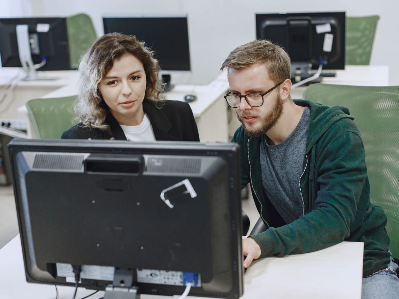 Zwei Personen sehen gemeinsam auf einen Bildschirm in einem Büro