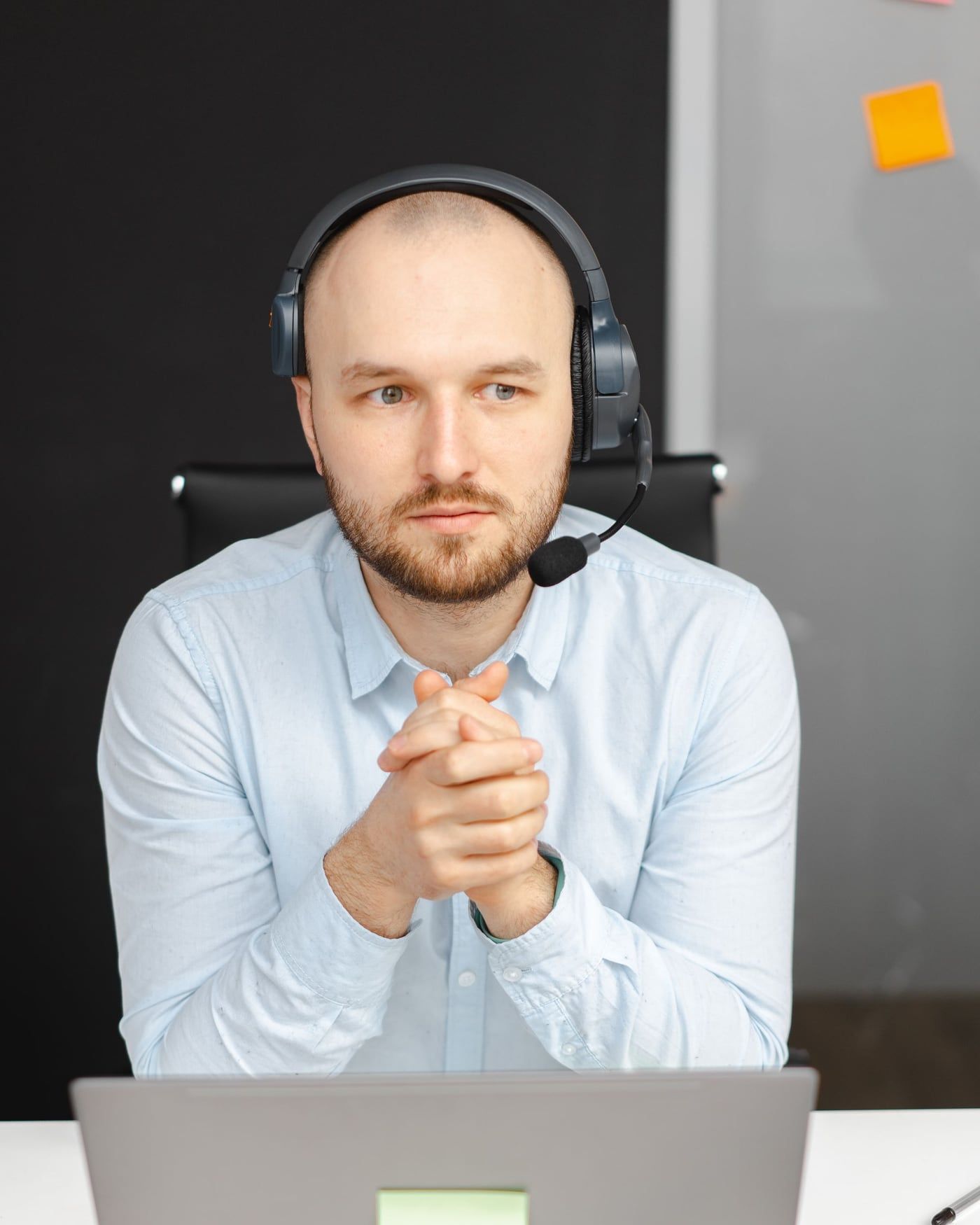 Ein Mitarbeiter mit Headset sitzt aufmerksam am Schreibtisch vor seinem Notebook